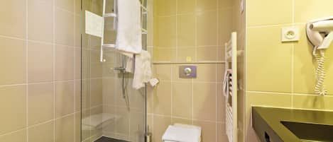 A bathroom with a glass shower enclosure, a toilet, a towel rack, and a hairdryer mounted on the wall.