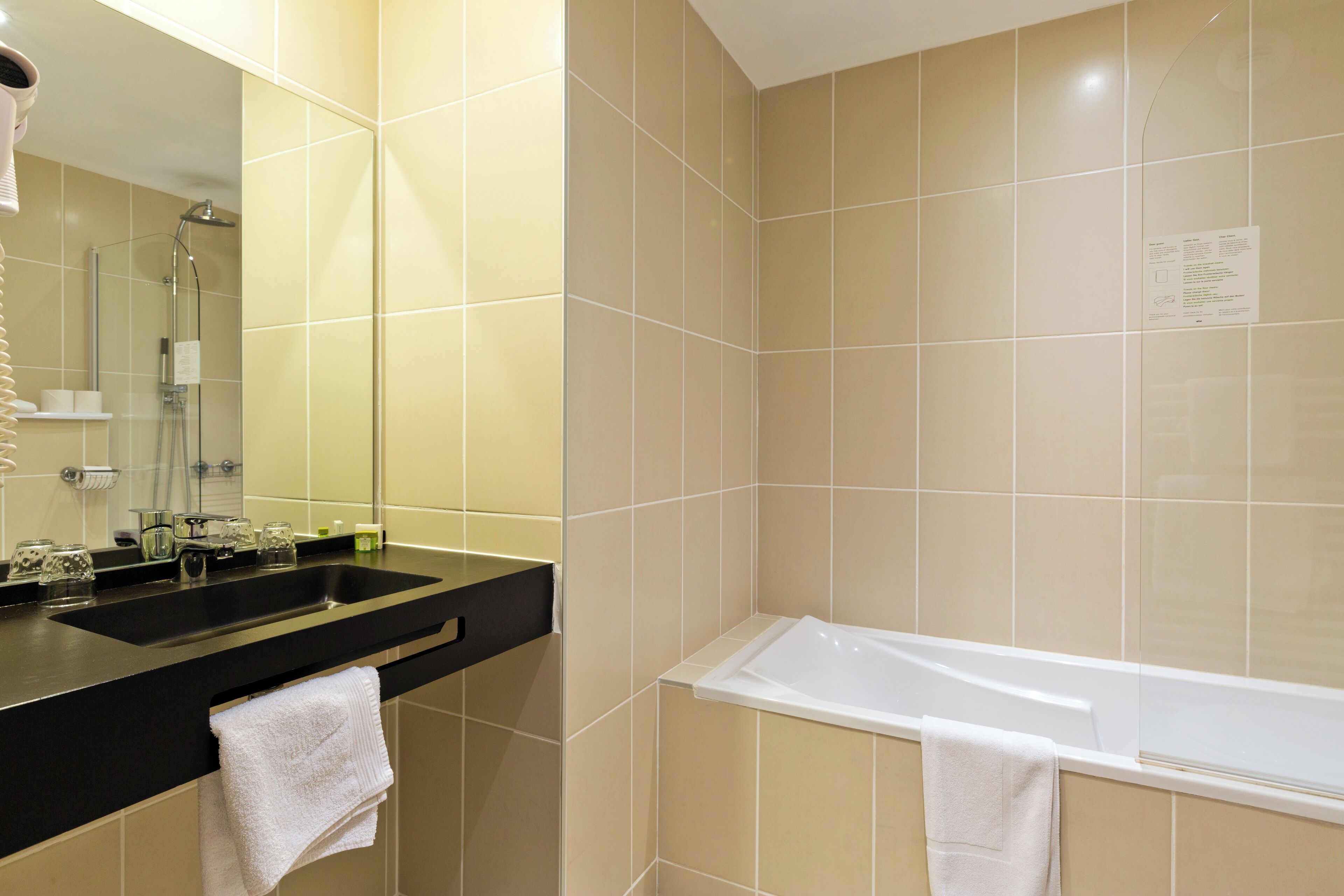 Un baño moderno con encimera negra, un lavabo, un espejo, una ducha y una bañera.