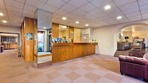 Un vestíbulo de hotel con recepción, zona de estar y bar.