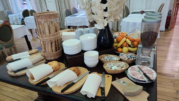 Montaje de desayuno buffet con pan, bollería, frutas y salsas.