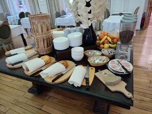 A breakfast buffet setup with bread, pastries, fruits, and condiments. - Hôtel du Parc (Mont-Dore)