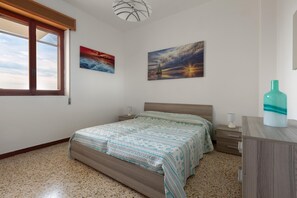 Cozy retreat with a large bed, two bedside tables, and a dresser, set against a serene backdrop of framed seascapes.