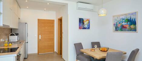 Une cuisine moderne avec une porte en bois, une table à manger avec quatre chaises et un tableau accroché au mur.