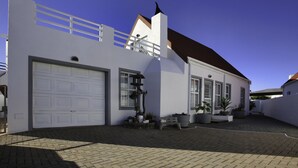A modern two-story house with a white exterior, a garage, and a small patio area with potted plants and a bench.