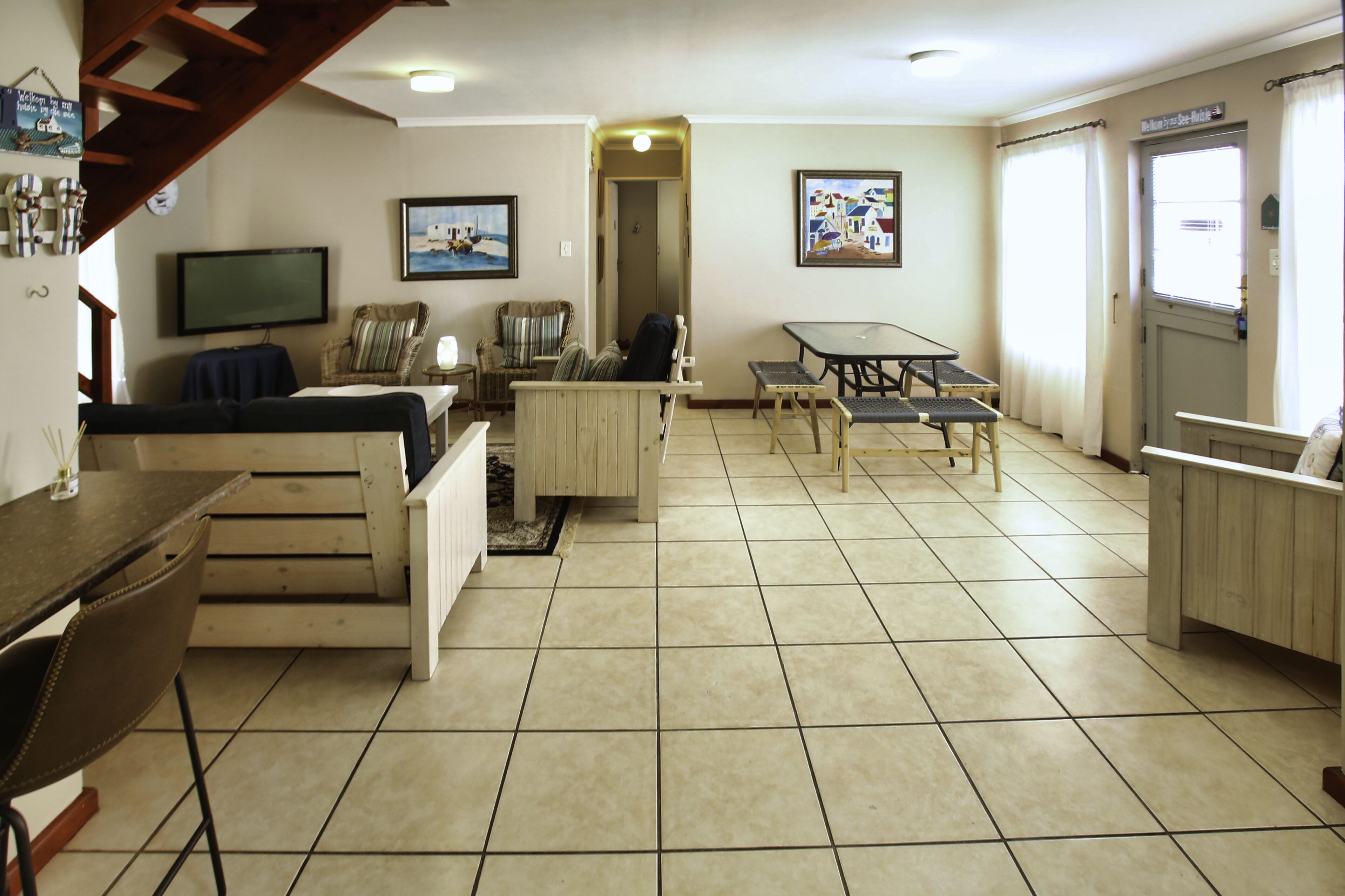 A spacious room with a wooden table, chairs, a sofa, and a television.