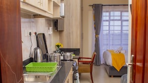 Una cocina compacta con armarios de madera, un lavamanos y un comedor con una silla y una mesa.
