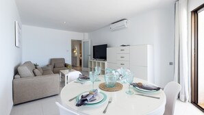 Un salon moderne comprenant un coin repas, un canapé, un téléviseur et un meuble.