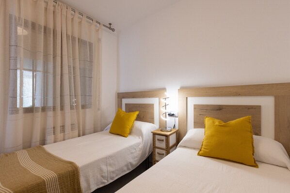 A hotel room with two beds, each with a wooden headboard and a bedside table with a lamp. - Stunning views, 2-bedroom apartment, Salou centre UHC SANTILLANA 129 (Salou)