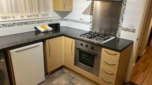 Una cucina compatta con piano cottura a gas, forno e lavastoviglie.
