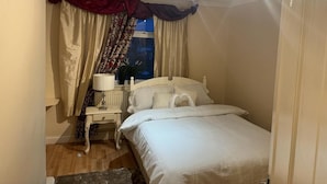 Una camera da letto con un letto, un comodino, una lampada e delle tende.