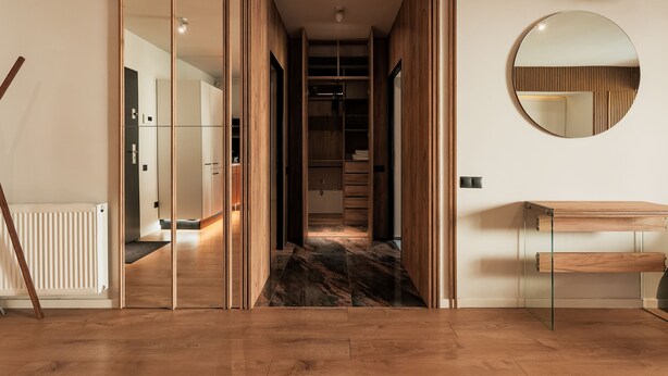 A modern interior with a wooden floor, a mirrored wall, and a built-in bench. - Nest Inn Mirror Apartment (Cluj-Napoca)