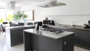 Una cocina moderna con una isla central, electrodomésticos de acero inoxidable y un ventanal grande.
