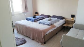 A bedroom with a bed, two bedside tables, a chair, and a window with curtains.