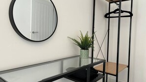 A room with a round mirror, a glass console table, a potted plant, and a black metal shelving unit with a wooden top. - Shrewsbury House, 3 En-Suites (Shrewsbury)