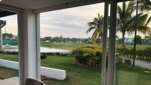 La vue depuis cette chambre, avec ses grandes fenêtres, donne sur un terrain de golf, une piscine et une pelouse parfaitement entretenue.