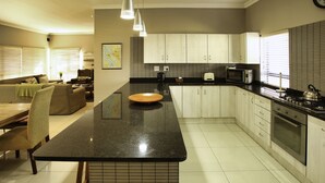 A modern kitchen with a central island, a dining area with a table and chairs, and a living room with a sofa and a coffee table.