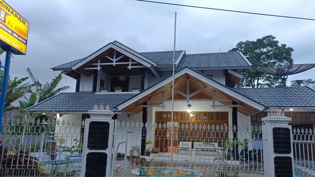 A two-story house with a tiled roof, a gated entrance, and a small pool area. - OYO 93706 Penginapan Syariah Hj. Kenan (Koto Tinggi)