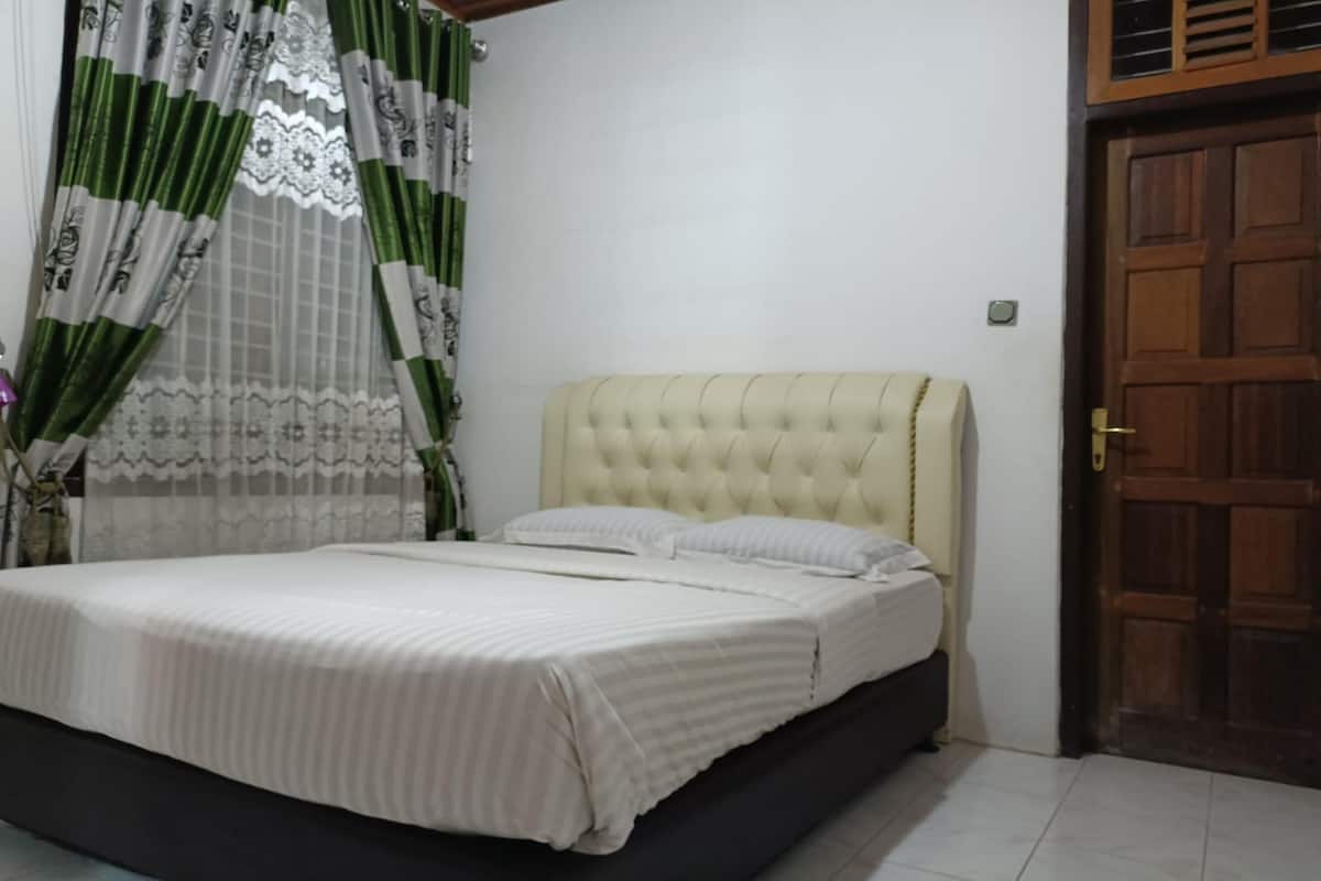 A bedroom with a bed, curtains, and a wooden door.