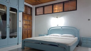 A bedroom with a blue bed, a wardrobe, and a nightstand. - OYO 93706 Penginapan Syariah Hj. Kenan (Koto Tinggi)