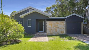 A two-story house with a stone facade, a front door, and a garage. - Russell Street Retreat (Hawks Nest)