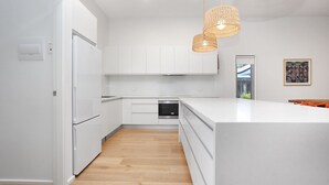 Una cocina moderna con armarios blancos, horno integrado y una isla grande.