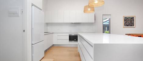 A modern kitchen with white cabinetry, a built-in oven, and a large island.