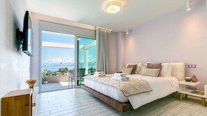 Un dormitorio moderno con una cama grande, un televisor montado en la pared, una mesita de noche y vistas al exterior.