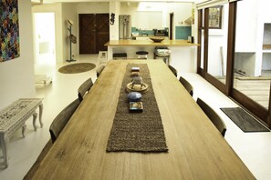 Un comedor con una larga mesa de madera, sillas y un adorno central.