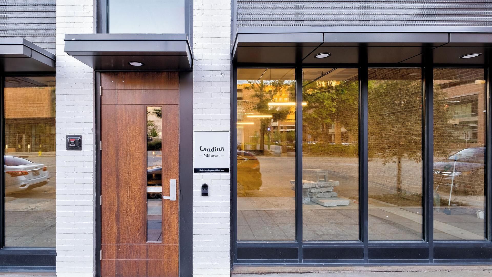 A building entrance with a wooden door and large glass windows.