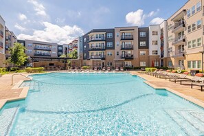 A swimming pool surrounded by multi-story residential buildings with balconies and outdoor seating areas. - Landing | Stunning 1BD, Pool, Yoga Studio (Austin)