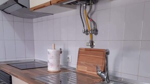 A kitchen with a stainless steel sink, wooden countertop, and a built-in dishwasher. - Apartamento T1 em Quarteira! (Quarteira)