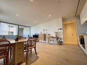 Een moderne keuken met een eethoek, houten meubels en grote ramen.