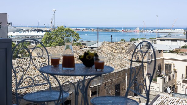 A terrace with a table and chairs overlooking a harbor with boats and cranes. - Palermonamour Art Gallery Suite (Palermo)