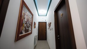 A hallway with a wooden door, a framed picture on the wall, and a ceiling light. - Palermonamour Art Gallery Suite (Palermo)