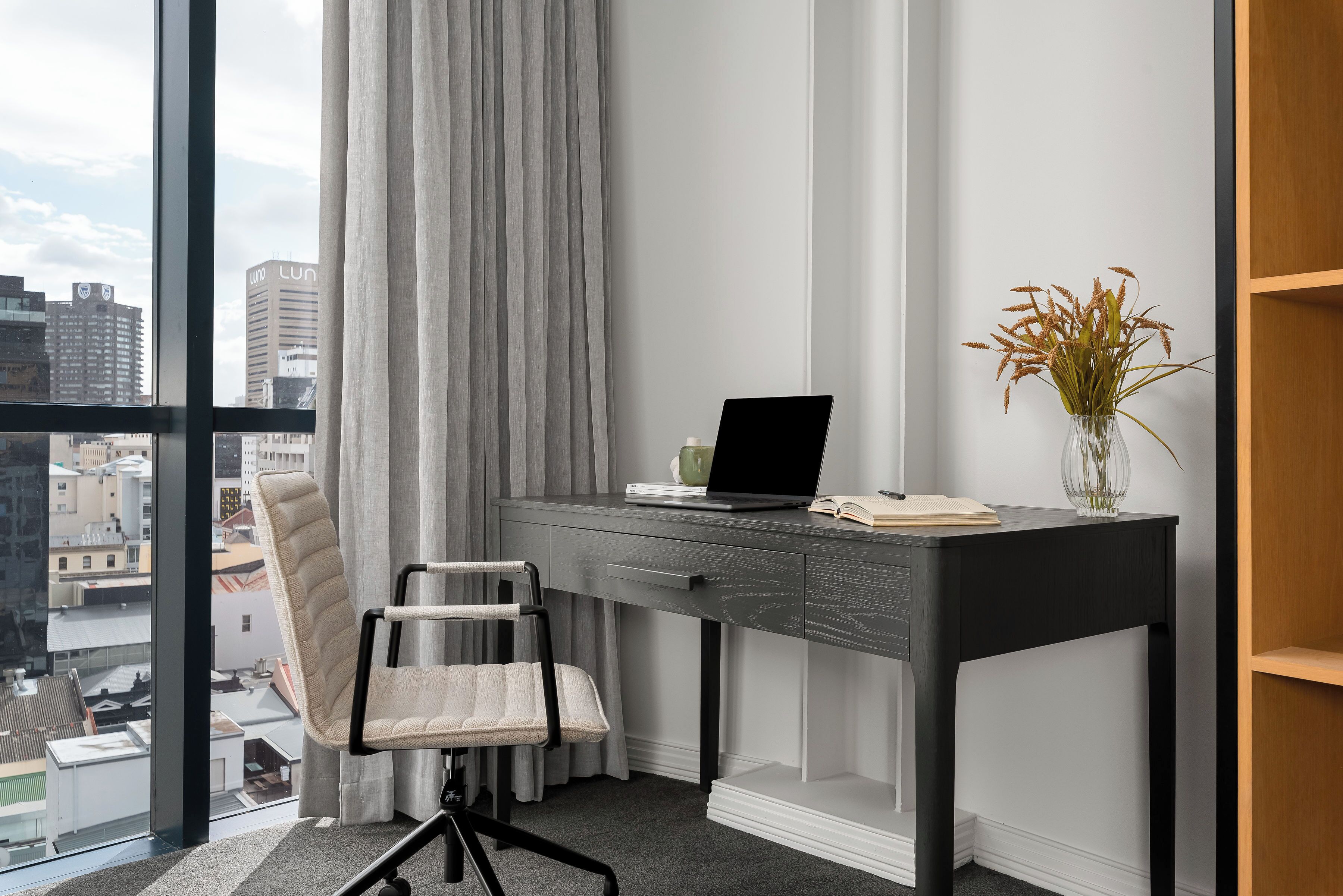 A modern office space with a desk, chair, and a view of the city through large windows.