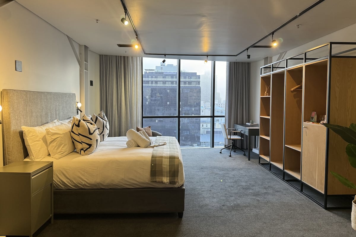 Quarto de hotel moderno com uma cama grande, uma escrivaninha e um guarda-roupa.