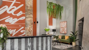 A modern reception area with a marble reception desk, a green sofa, and a potted plant. - Neighbourgood Loop (Cape Town)