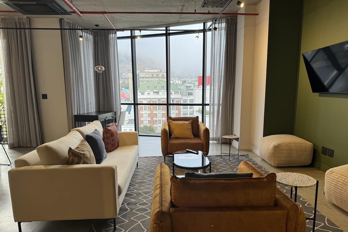 Uma sala de estar moderna com sofá, poltronas, mesa de centro e televisão na parede.