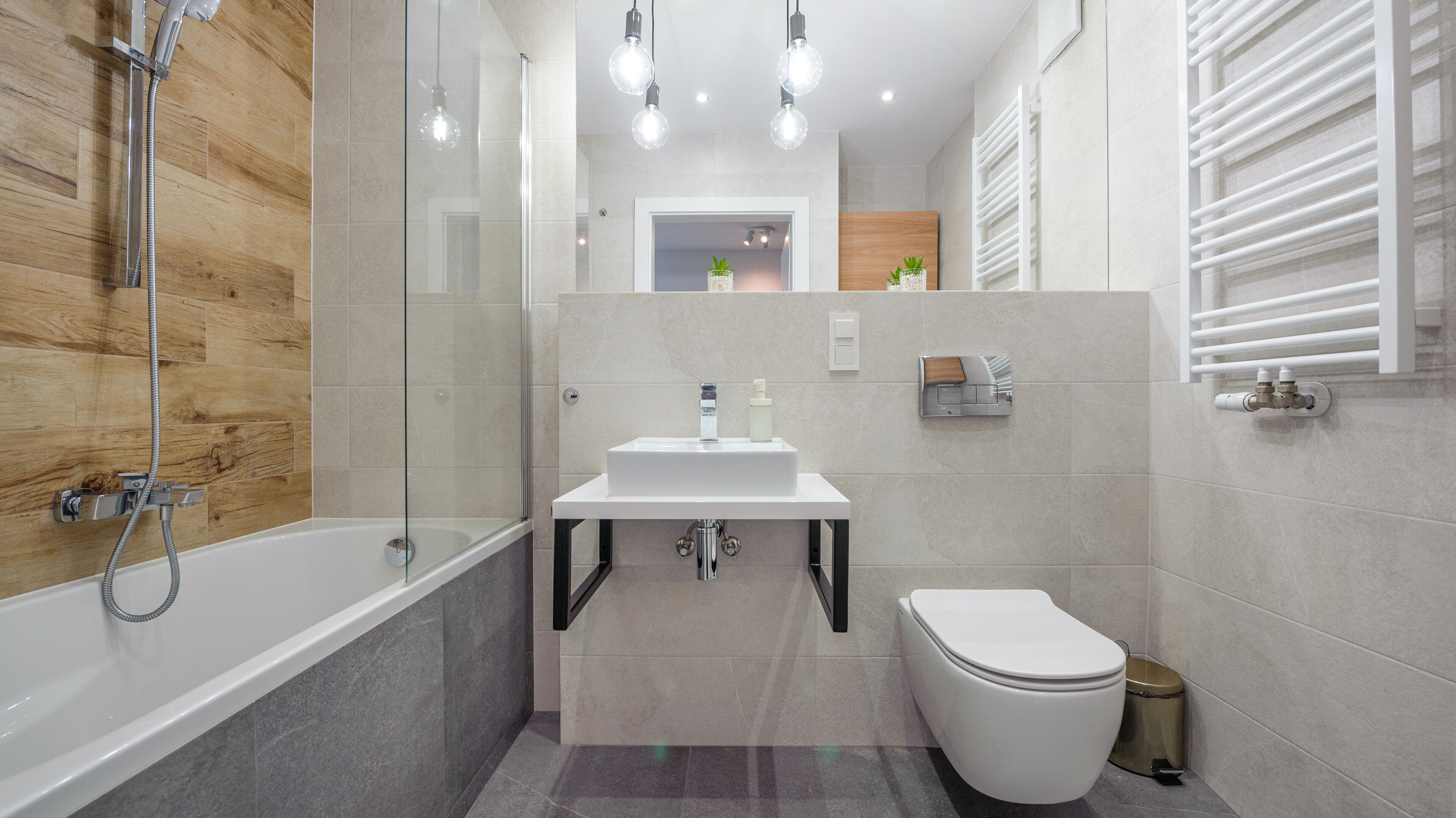 Un bany modern amb dutxa envidriada, un lavabo blanc i un vàter.