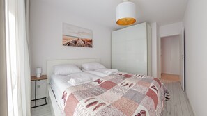 Quarto com cama, mesa de cabeceira com abajur, um quadro na parede e um guarda-roupa.