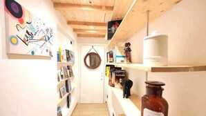 Ein schmaler Flur mit Holzbalken an der Decke, Bücherregalen an beiden Seiten und einem Honigglas rechts.