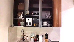 Eine kleine Küche mit Spüle, Arbeitsplatte und offenen Regalen darüber.