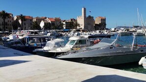 Ein Yachthafen mit vertäuten Booten, ein schlösserähnliches Gebäude und ein klarer, blauer Himmel.