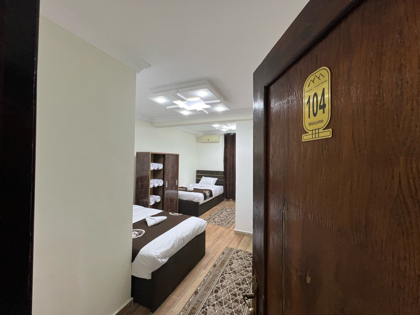 A hotel room with a wooden door marked "104 Welcome".
