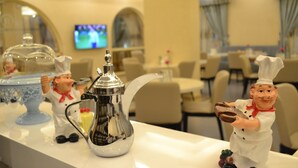 Un vestíbulo de hotel con una zona de recepción que presenta figuritas decorativas con motivos de cocina, una cafetera y un jarrón azul.