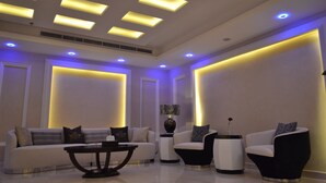 Una sala de estar moderna con un sofá, sillones, una mesita de centro y una mesita auxiliar con una lámpara.
