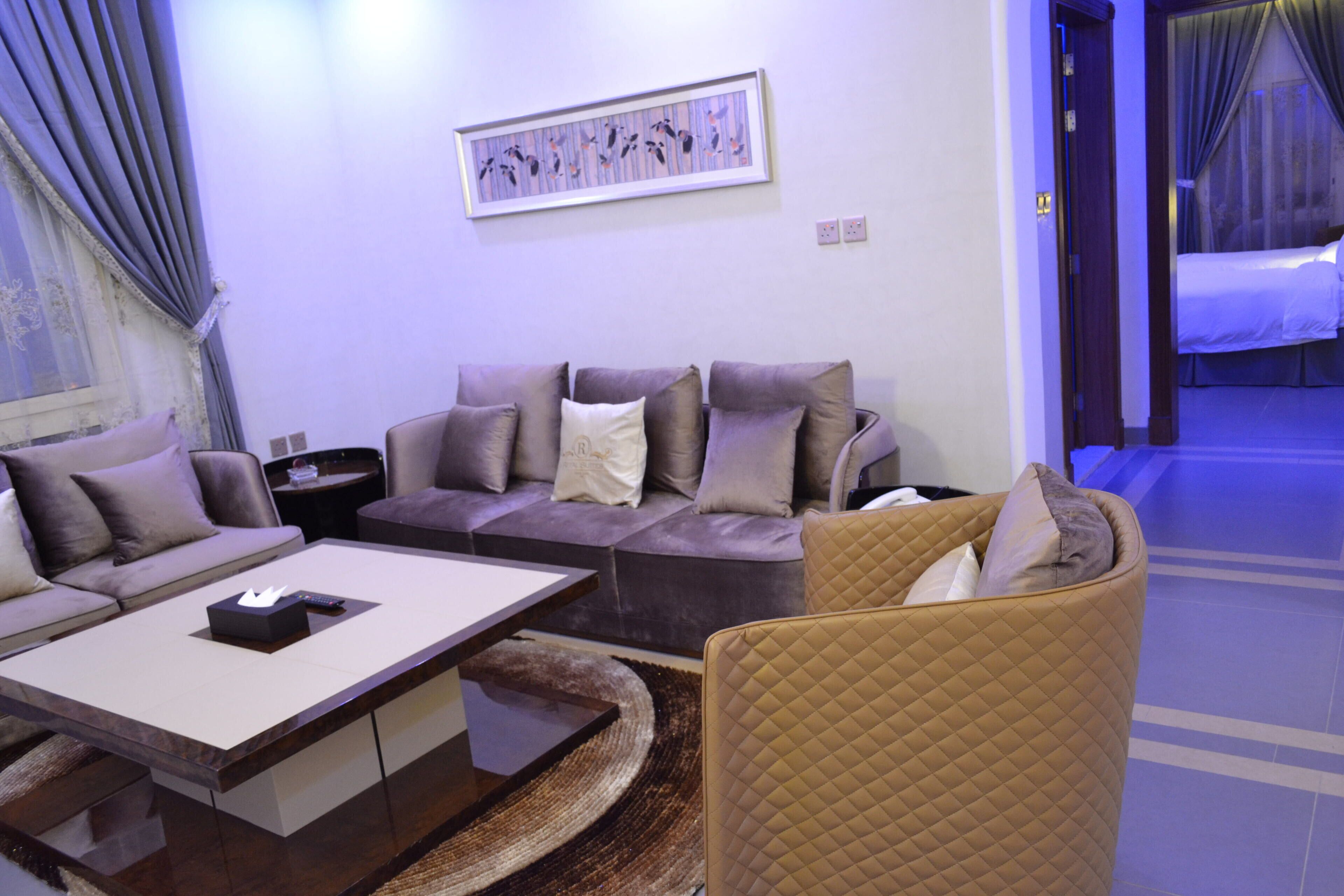 A modern living room with a sectional sofa, a coffee table, and a quilted armchair.