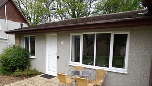 A small house with a patio, a table with chairs, and a door with a number 79 sign.