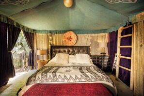 Une chambre spacieuse avec un grand lit, une tête de lit en bois et une vue sur l’extérieur.