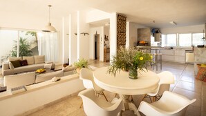 Een moderne woonkamer met een bank, salontafel en een eethoek met stoelen en een tafel.